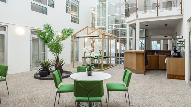 Loungeyta med gröna stolar och högt i tak 