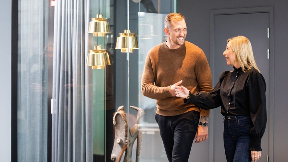 två personer går i en korridor och skakar samtidigt hand.