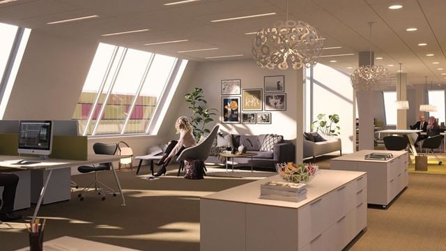 Kontorshuset Origo i Hyllie har snedtak och balkonger på varje våningsplan. En kvinna sitter på en kontorsstol intill snedtaket. 