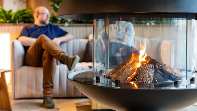 Bild på man som sitter bakom en en eldstad